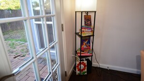 Une bibliothèque remplie de livres et une lampe dans une pièce dont la porte donne sur un espace extérieur.