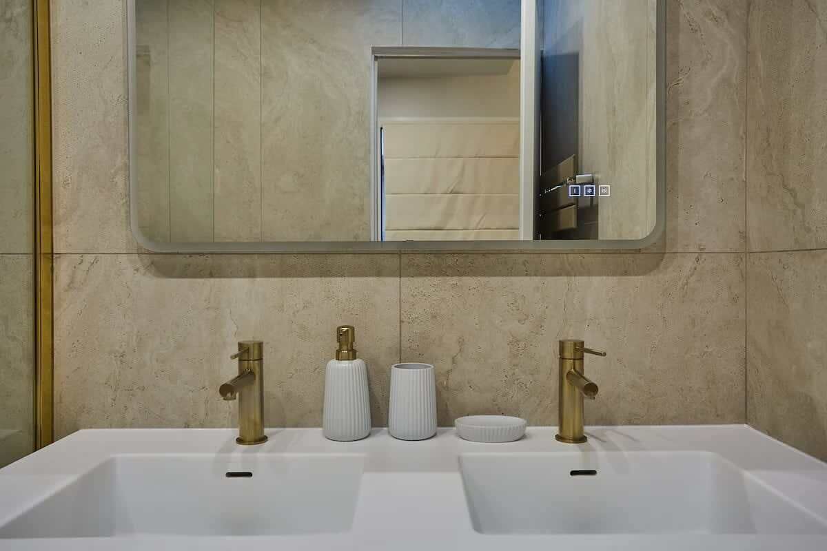 Une salle de bain avec deux lavabos, un miroir et un porte-serviettes.