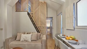 A modern living space with a sofa, dining table, and staircase. - Place de la Bastille Cozy and Modern 2BD (Paris)