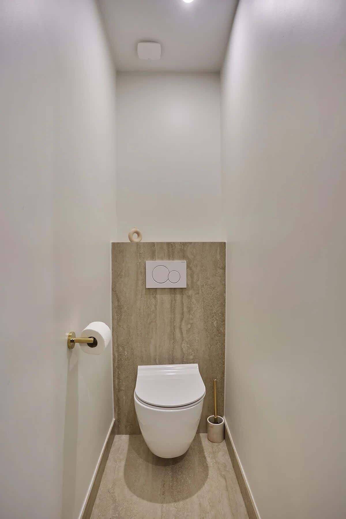 A modern bathroom with a toilet, a toilet paper holder, and a bidet.