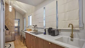 A modern kitchen with a white countertop, a built-in oven, and a gold faucet. - Place de la Bastille Cozy and Modern 2BD (Paris)