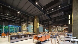 Un restaurante espacioso con techos altos, ventanas amplias y mobiliario moderno.