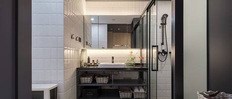 Un baño moderno con cabina de ducha de vidrio, lavamanos blanco y tocador negro.