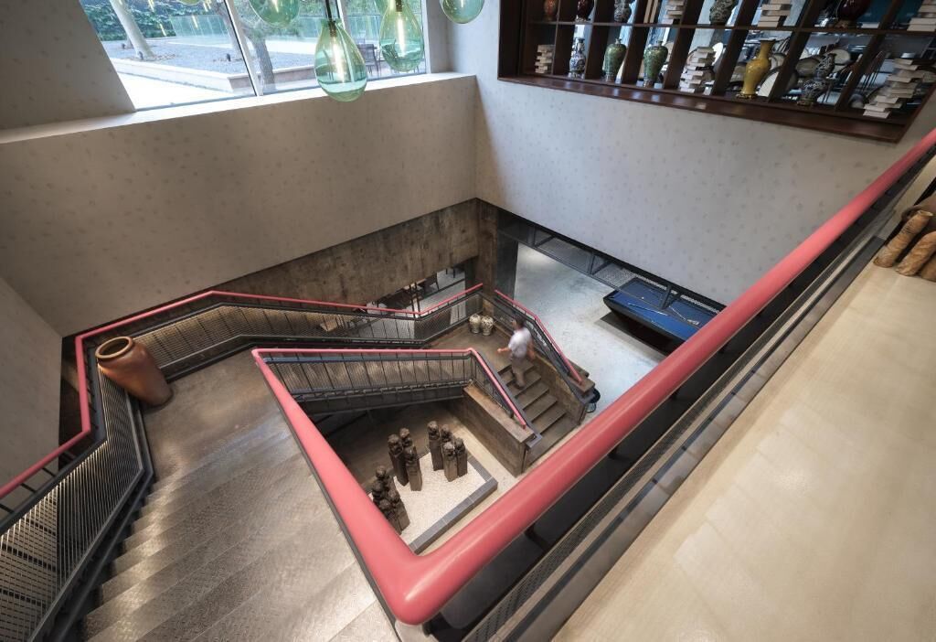 A modern interior with a central staircase, a seating area, and a display of decorative items.