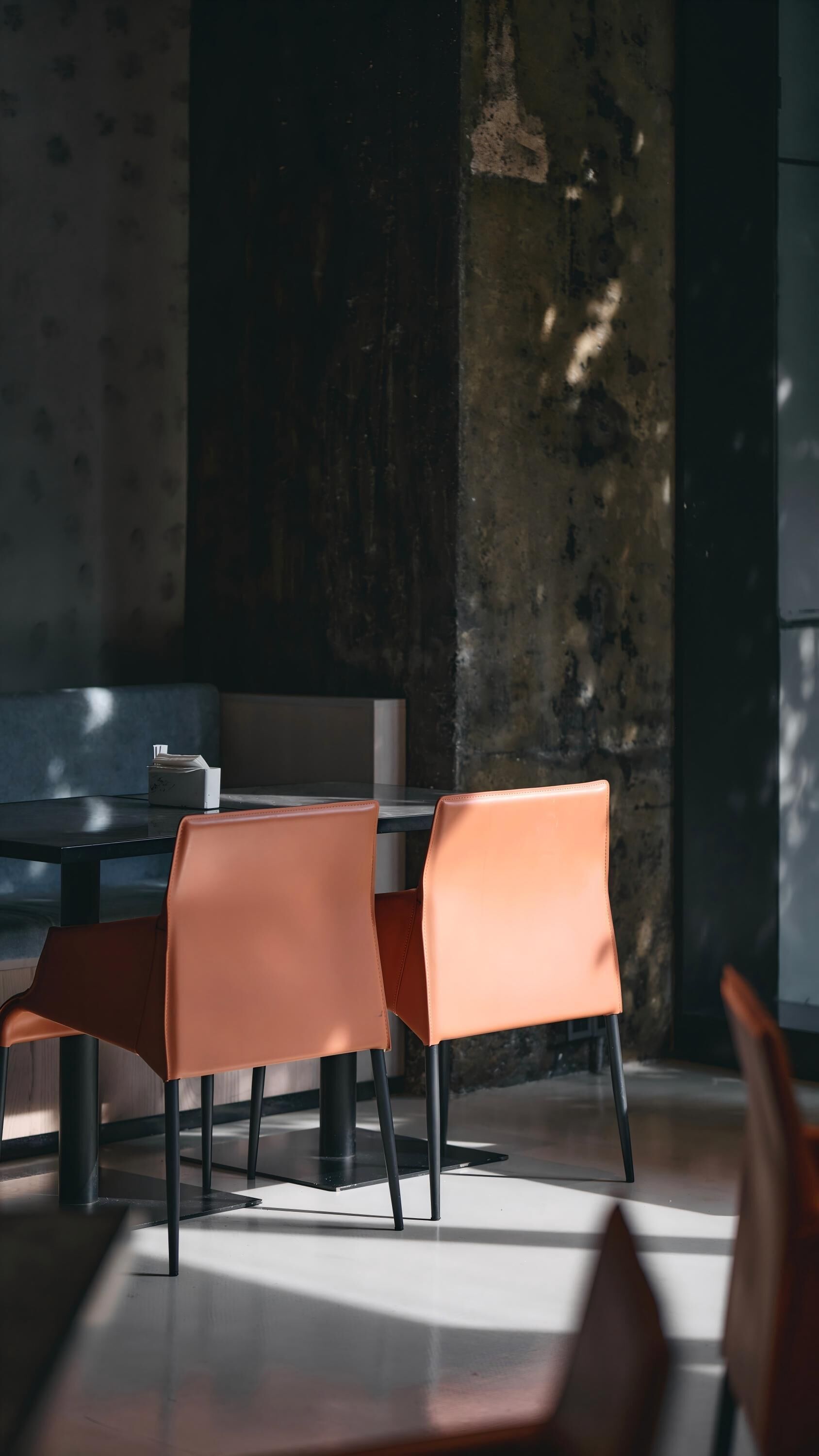 A modern dining area with a table and chairs, a patterned wall, and a large window.