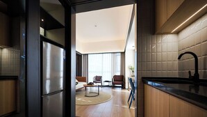Una cocina moderna con un refrigerador de acero inoxidable, armarios de madera y una encimera negra.