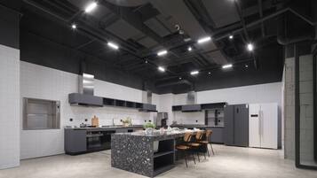 A modern kitchen with a central island, built-in appliances, and a high ceiling with exposed ductwork.