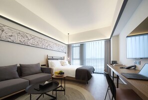 A modern hotel room with a bed, sofa, desk, and a large abstract artwork on the wall. - Shanghai T Plus Hotel Residence (Shanghai)