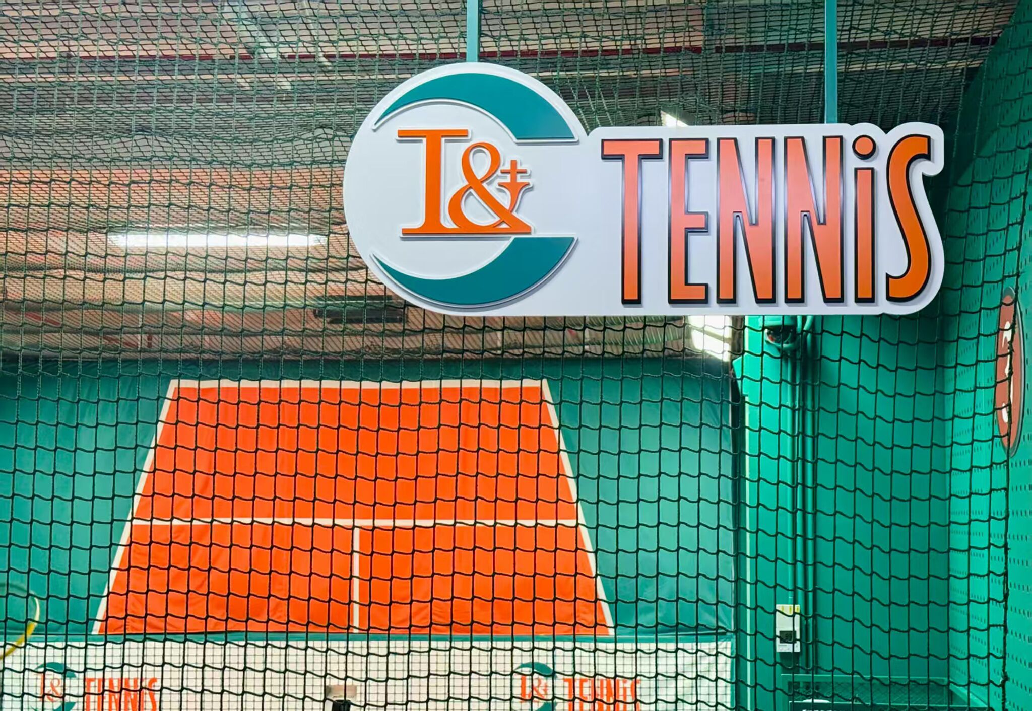 Un court de tennis avec un filet et une pancarte sur laquelle on peut lire : « T&T TENNIS ».