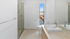 Un baño moderno con ducha envuelta en vidrio, inodoro y un espejo grande.