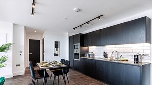 Una cocina moderna con armarios oscuros, una isla central y un comedor con mesa y sillas.
