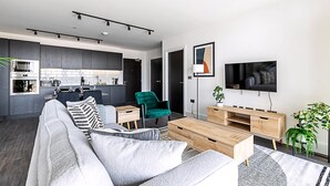 Un apartamento moderno con cocina, sala de estar y televisor montado en la pared.
