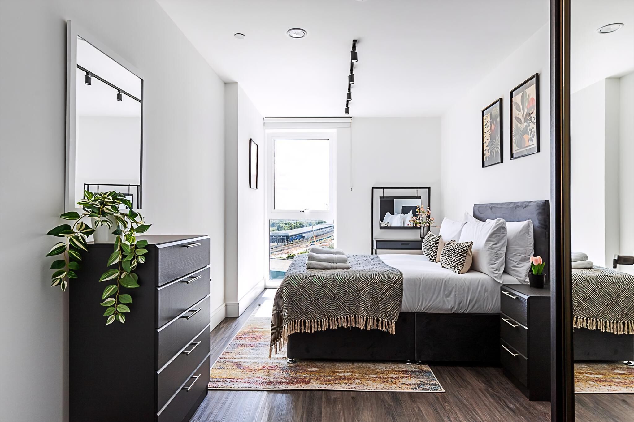 Une chambre moderne avec un grand lit, une commode, un miroir et une vue sur un pont.