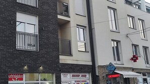Un edificio de varios pisos con balcones, una farmacia y diferentes comercios.