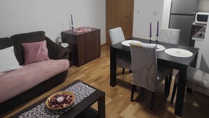 Un espacio habitable compacto con sofá, mesa de comedor y zona de cocina.