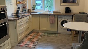 Une cuisine moderne équipée d’un four encastré, d’un lave-linge et d’un coin repas avec une table et des chaises.
