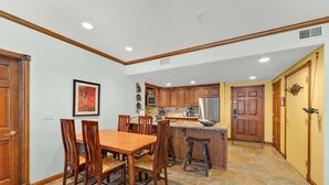 A spacious kitchen with wooden cabinets, a central island, and a dining area with a wooden table and chairs. - 2BR Main St Condo, Walk to Ski Lift! (Park City)