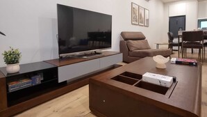 Un salon moderne doté d’un téléviseur à écran plat, d’un canapé marron, d’une table basse et d’un coin repas avec une table et des chaises.