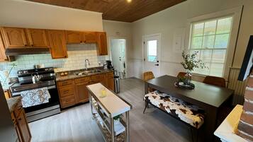 A spacious kitchen with wooden cabinets, a stainless steel stove, and a dining area with a bench and table.