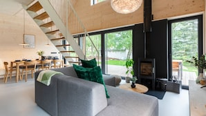 Una sala de estar moderna con un sofá gris, una escalera de madera y una chimenea.