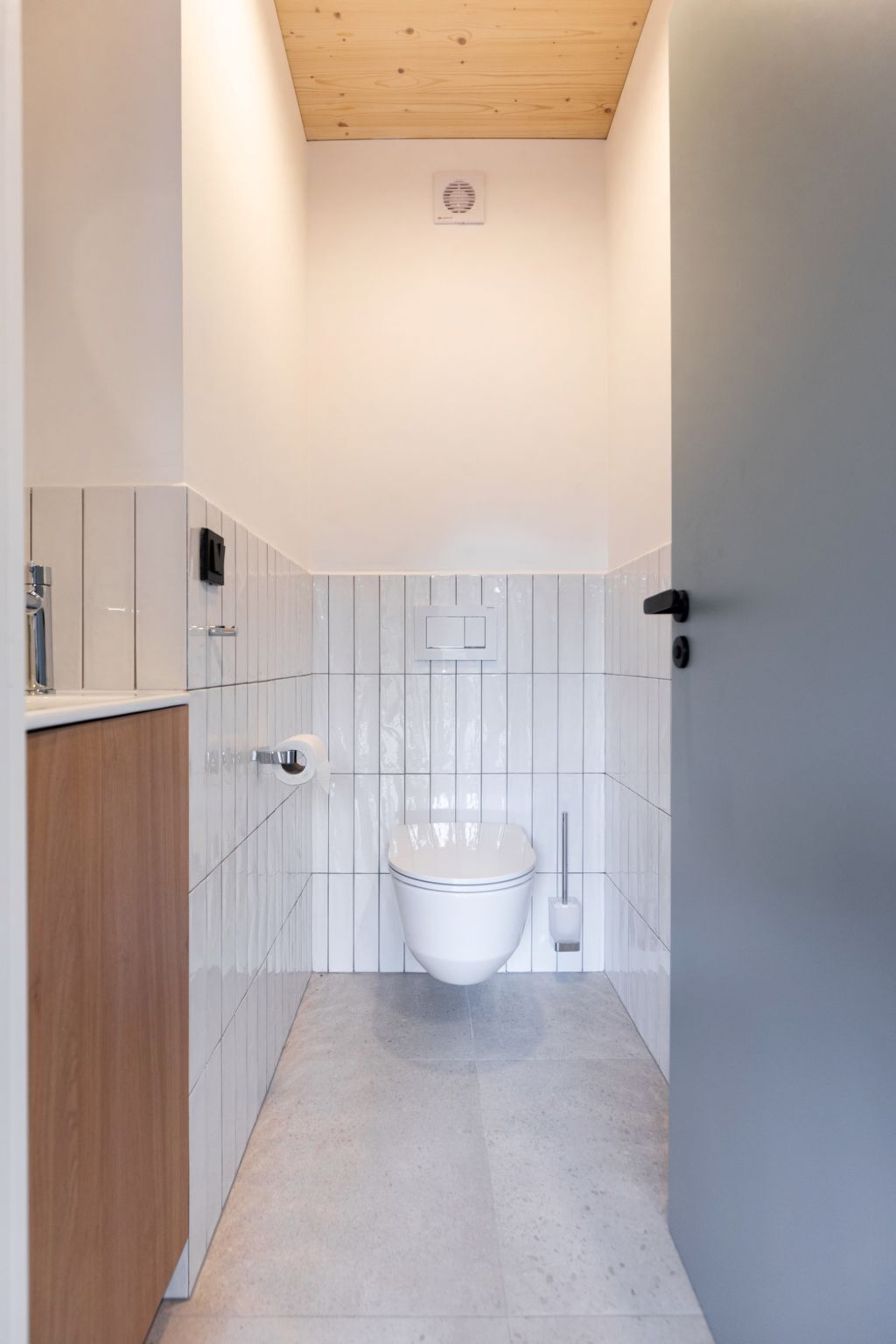 Un baño moderno con inodoro, bidé y un armario de madera.