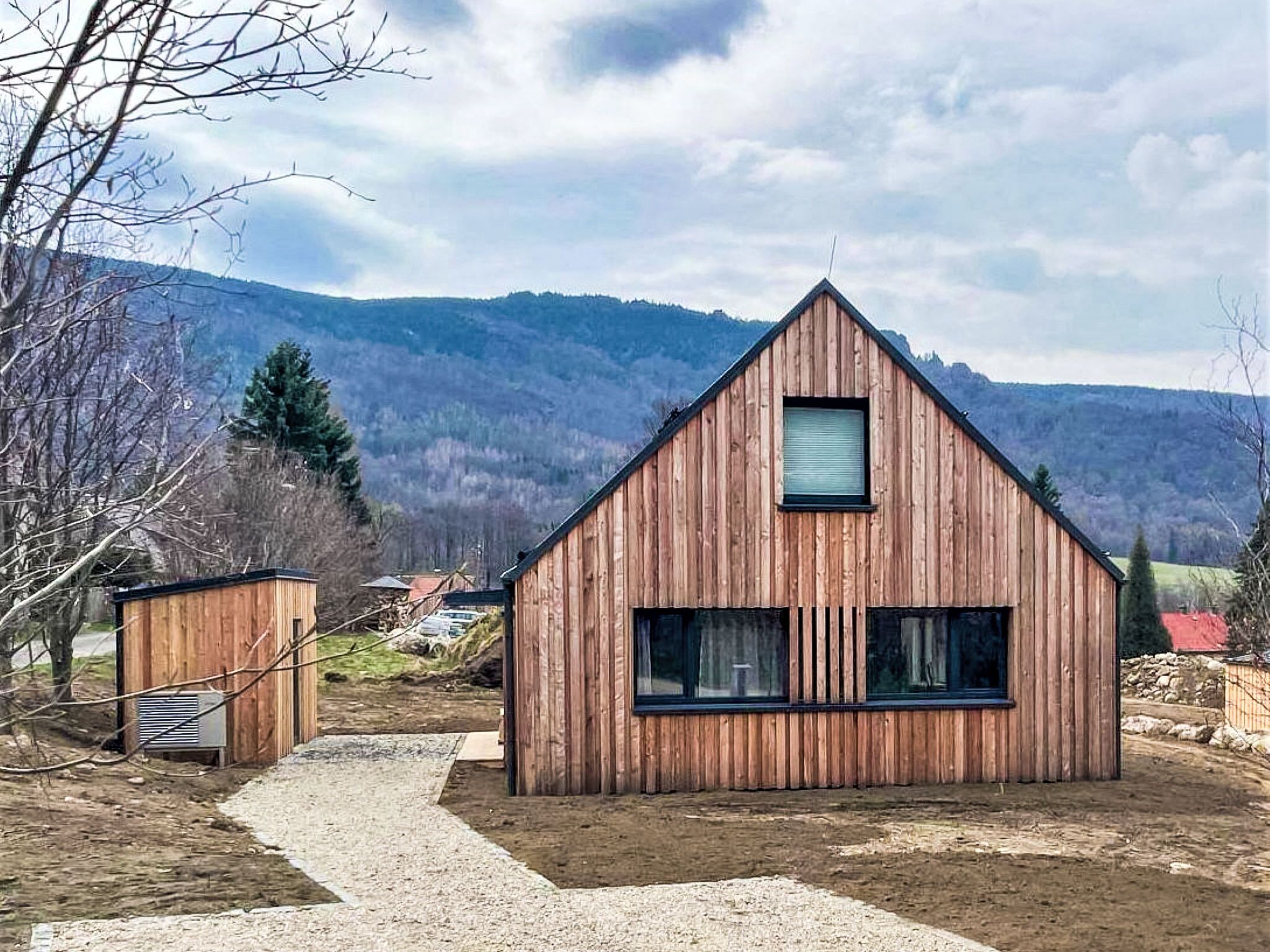 Eine Holzhütte mit einem Giebeldach, einem kleinen Fenster und einem Kiesweg, der dorthin führt.