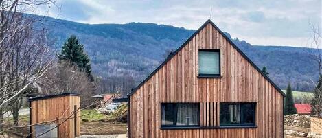 Eine Holzhütte mit einem Giebeldach, einem kleinen Fenster und einem Kiesweg, der dorthin führt.