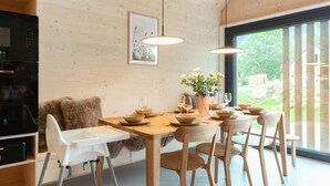 Ein moderner Essbereich mit Holztisch und -stühlen, Pendelleuchten und Blick ins Freie.