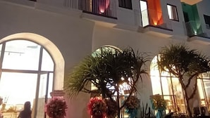 A multi-story hotel with balconies, large windows, and outdoor seating areas with plants. - Nang Hotel - Phu Quy (Phu Quy)