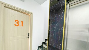 A hallway with a wooden door marked "3.1", a marble wall, and an elevator. - Nang Hotel - Phu Quy (Phu Quy)