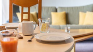 Une table de petit-déjeuner avec une assiette, une tasse, un verre d’eau et un jus de fruits.