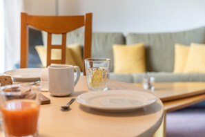 Une table de petit-déjeuner avec une assiette, une tasse, un verre d’eau et un jus de fruits.