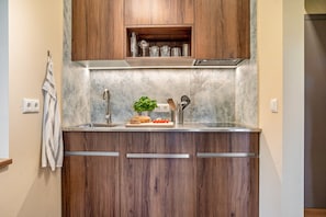 A kitchen with wooden cabinets, a marble countertop, and a stainless steel range hood.