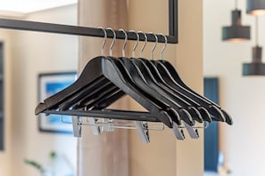 A black hanger rack with multiple hangers, a metal support structure, and a blurred background with a framed picture.