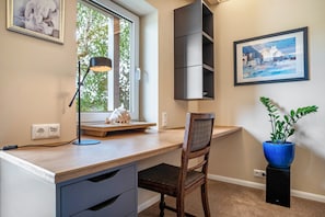 A modern office space with a desk, chair, lamp, and artwork on the walls.