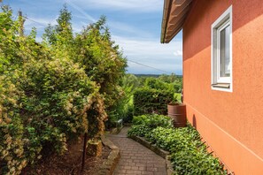 Un estrecho sendero de ladrillo que lleva a una casa de fachada roja y una ventana.