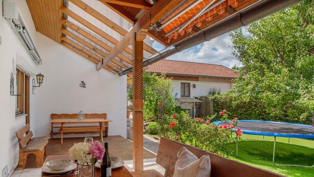 Un patio exterior con mesa de madera, bancos y un trampolín.