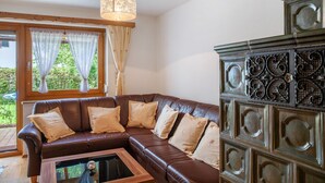 Un sofá de cuero marrón con cojines color beige, una mesa de centro de madera y un aparador decorativo con diseños intrincados.