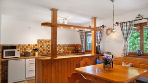 Una cocina con isla de madera, electrodomésticos blancos y una zona de comedor con mesa y sillas.