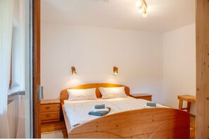 Un dormitorio con una cama de madera, dos mesitas de noche y lámparas fijadas a la pared.