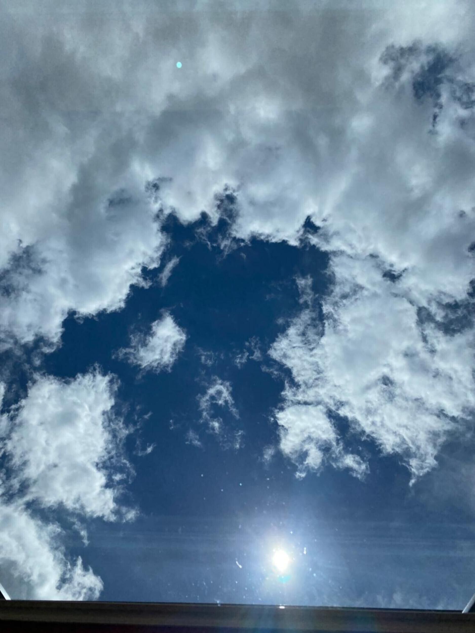 A view of the sky with clouds and the sun.