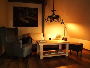 Un salon confortable avec un canapé, un fauteuil, une table basse et un tableau accroché au mur.