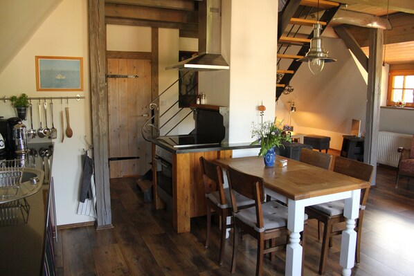A kitchen with wooden cabinets, a dining table, and chairs. There is a hanging light fixture above the table.