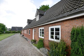 A residential building with a gravel driveway, brick walls, and a tiled roof.