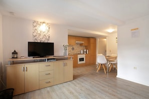 A modern kitchen with wooden cabinets, a built-in oven, and a dining area with a table and chairs.