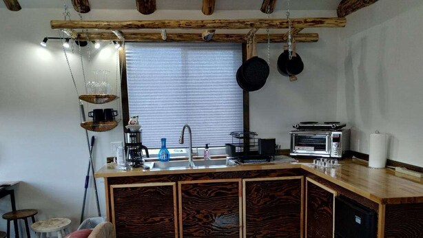 A kitchen with a wooden island, a sink, a stove, and hanging pots. - Windy Ridge Cabin
Babb/St.Marys (Babb)