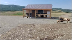 A rustic cabin with a metal roof, a wooden porch, and a gravel ground. - Windy Ridge Cabin
Babb/St.Marys (Babb)