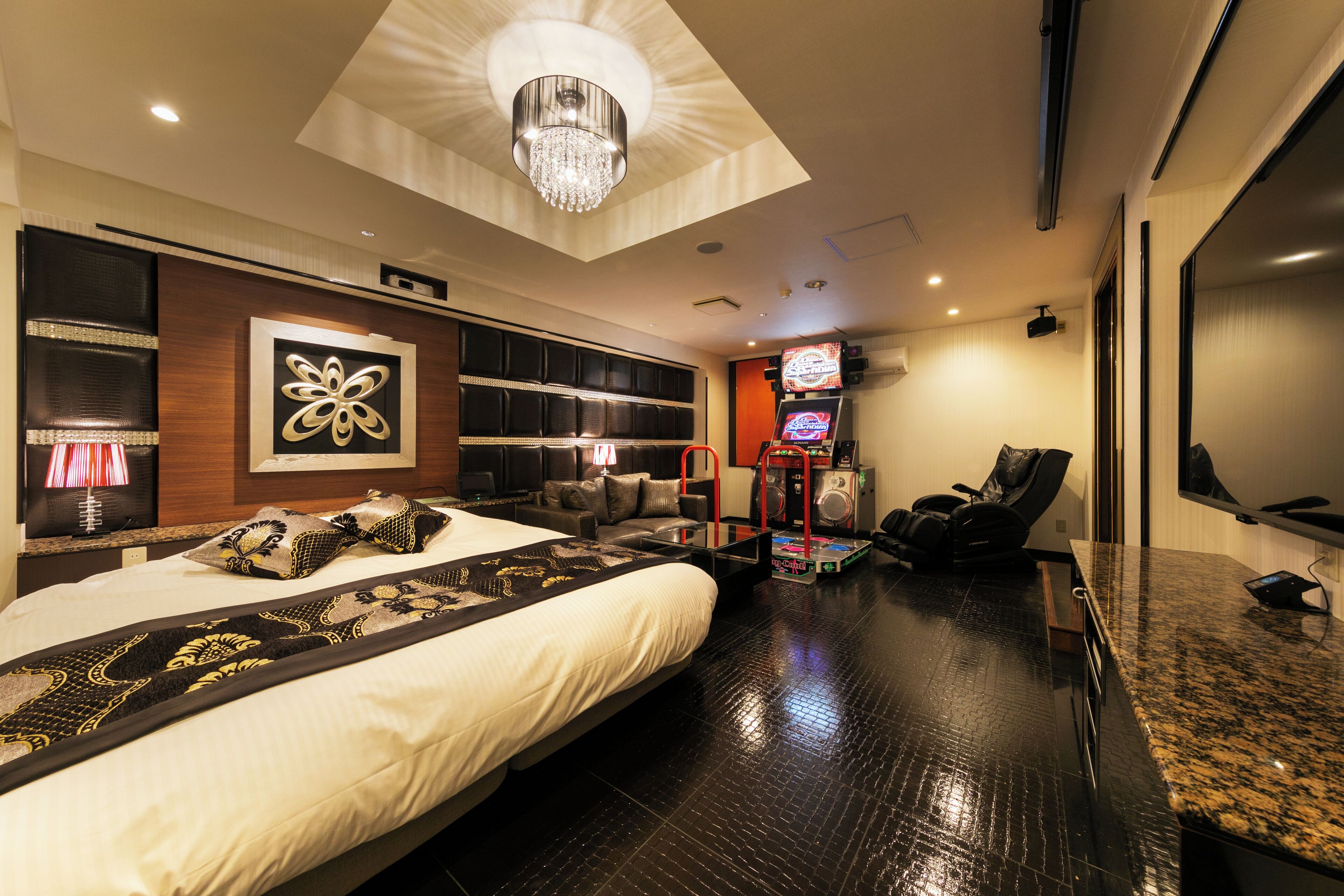 A modern hotel room with a large bed, a ceiling light, a TV, and a massage chair.