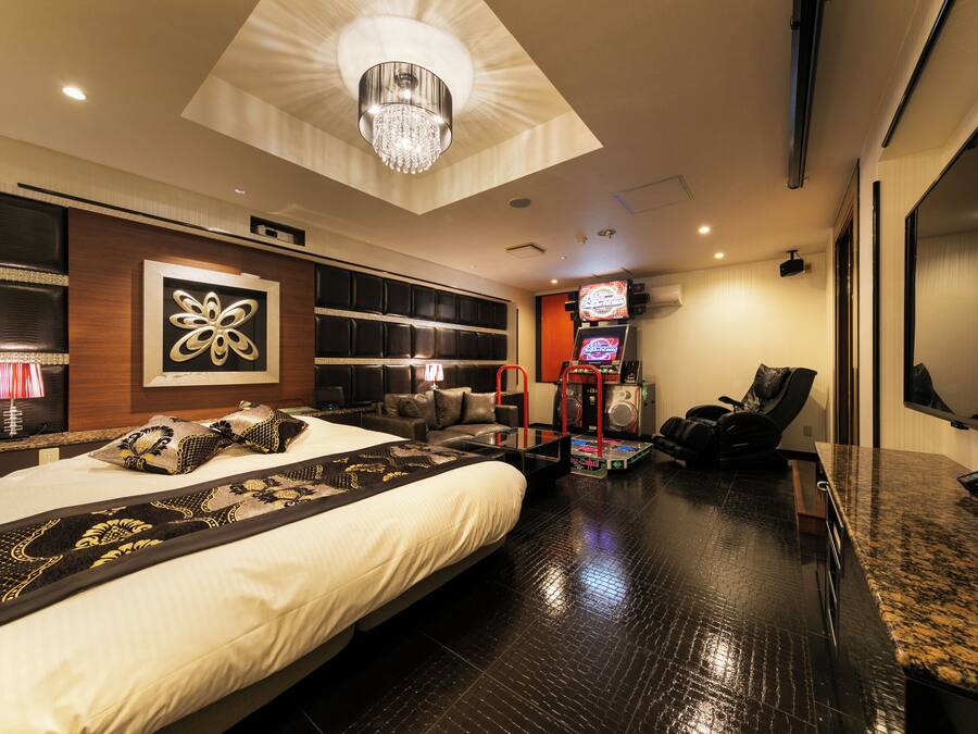 A modern hotel room with a large bed, a ceiling light, a TV, and a massage chair.