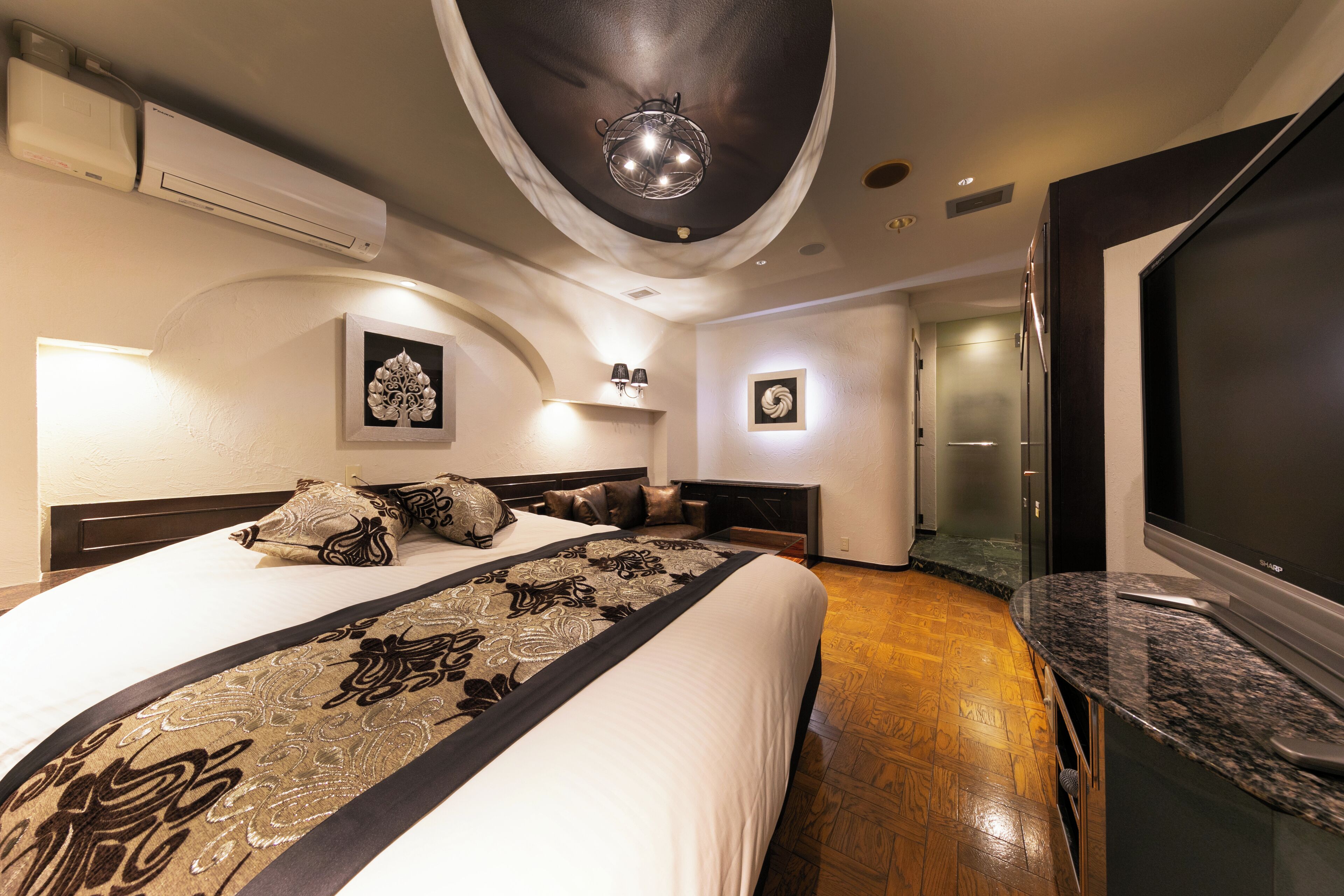 Una habitación de hotel moderna con una cama grande, un televisor de pantalla plana y una encimera de mármol.